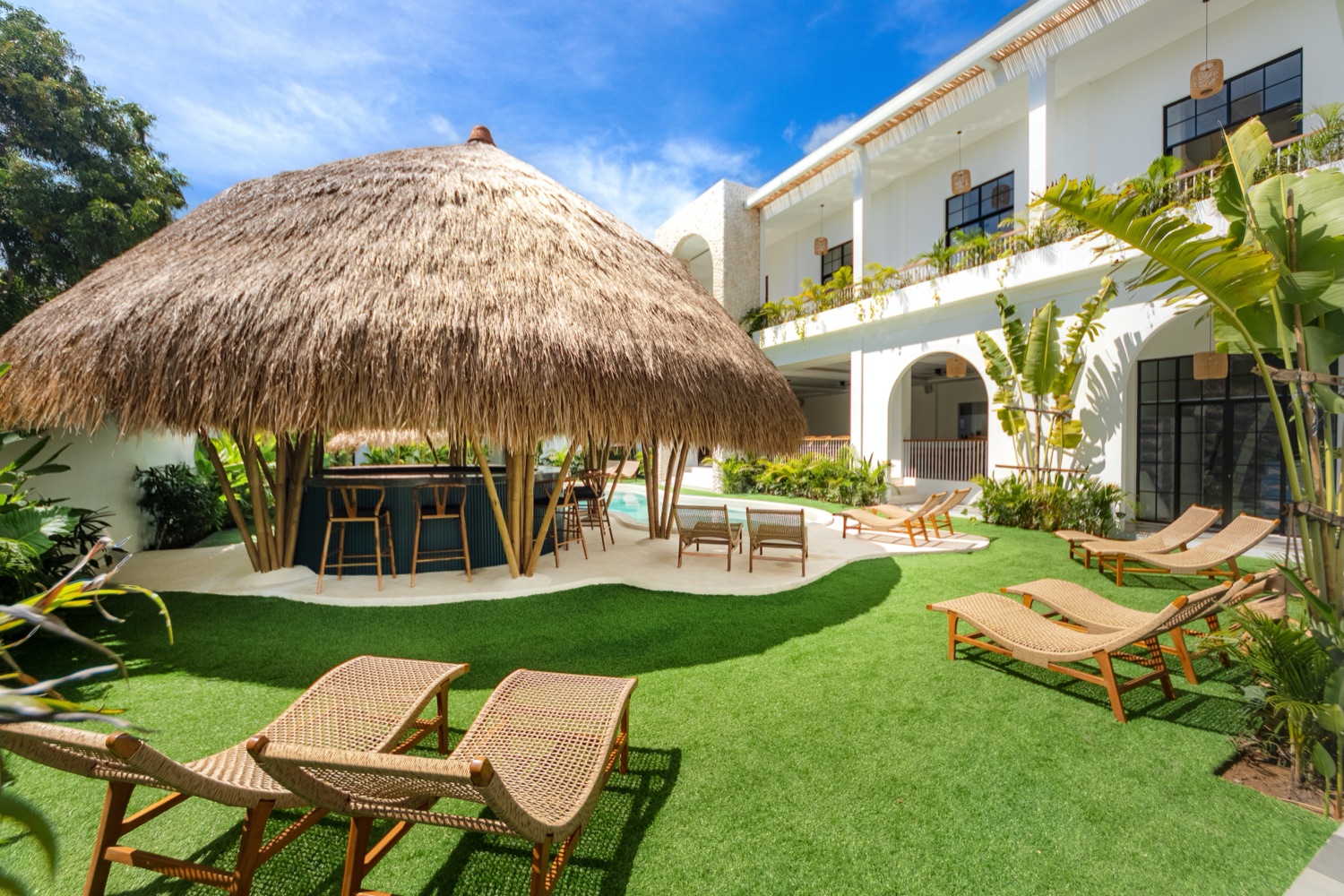Thatched palapa bar beside the lagoon pool with guest rooms above at The Lazy Lama Uluwatu