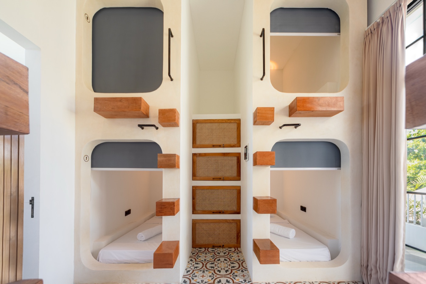 Numbered sleeping pods with rattan lockers in the mixed dorm at The Lazy Lama Uluwatu