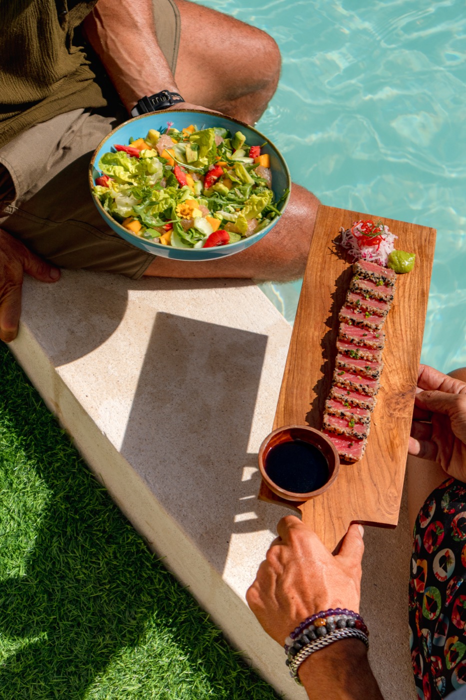 Guests sharing tuna tataki and salad by the pool